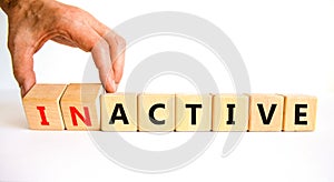 Active or inactive symbol. Businessman turns wooden cubes and changes the word Inactive to Active. Beautiful white table white