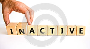 Active or inactive symbol. Businessman turns wooden cubes and changes the word Inactive to Active. Beautiful white table white