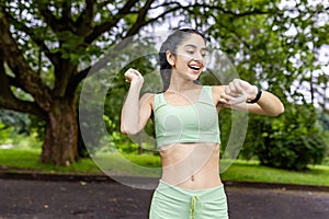 Active indian woman checking fitness tracker during outdoor workout in park