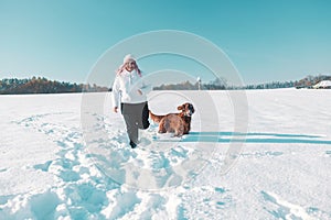 Active Irish Setter dog with woman running slow motion footage during the snowy walking, having fun in winter park. High