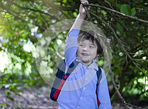 Active kid holding branch tree in the park, Excited boy carrying backpack getting adventure in the forest tree with school camp,