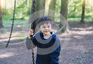 Active kid holding metal chains in playground, Child enjoying outdoors activity in a climbing rope chains in adventure park on