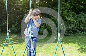 Active kid holding robe in playground, Child enjoying activity in a climbing adventure park on summer sunny day, Cute little boy h