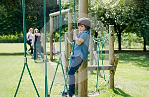 Active kid holding robe in playground, Child enjoying outdoors activity in a climbing adventure park on sunny day summer,