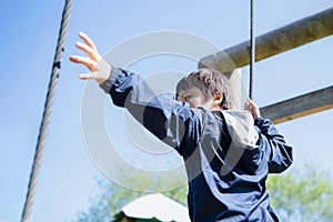 Active kid holding rope chains in playground, Child enjoying outdoors activity in a climbing chains in adventure park on sunny day