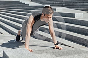 Active leisure and motivation. Guy with fitness tracker push up the city stairs