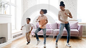 Black children and young babysitter dancing in living room