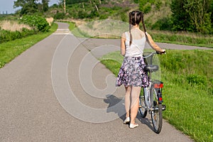 Active life. A woman with a bike enjoys the view at summer forest.