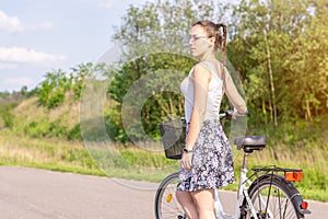 Active life. A woman with a bike enjoys the view at summer forest.