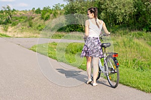 Active life. A woman with a bike enjoys the view at summer forest.