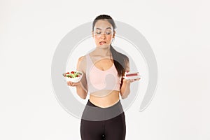 Active lifestyle, fitness and wellbeing concept. Portrait of indecisive and tempting cute asian girl trying resist