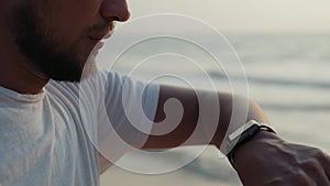 Active lifestyle man tourist looking tech smartwatch smart watch. Closeup macro close up arm beach touch screen on wrist