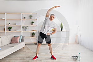 Active lifestyle. Mature man doing flexibility exercises for healthier living, working out at home, empty space