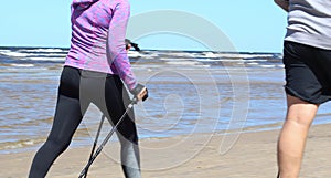 Active lifestyle with Nordic walking - active people walking on beach. Summer, spring activities in sunny day.