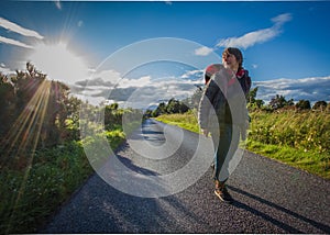 Active lifestyle people over 60, a woman walks along the road in the sun at sunset