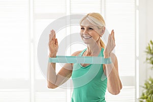Active Lifestyle. Smiling Senior Lady Exercising With Resistance Band At Home