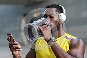 Active lifestyle. Strong african man drinking water after hard w