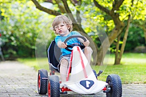 Active little boy having fun and driving toy car