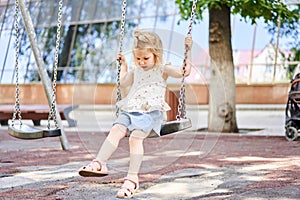 Active little child playing on climbing net and jumping on trampoline at school yard playground. Kids play and climb