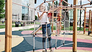 Active little child playing on rock climbing and jumping on school yard playground. Children play and climb outdoors on a sunny