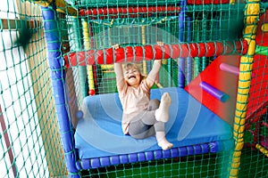 Active little girl playing in indoor playground. Happy joyful preschool child climbing, running, jumping and having fun