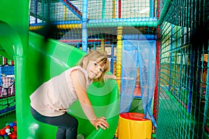 Active little girl playing in indoor playground. Happy joyful preschool child climbing, running, jumping and having fun