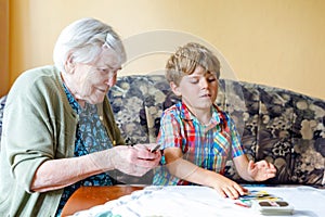 Active little preschool kid boy and grand grandmother playing card game together at home