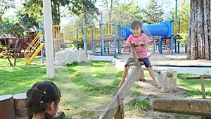 Active little sisters playing on a seesaw in the outdoor playground. Happy child girls smiling and laughing on children playground