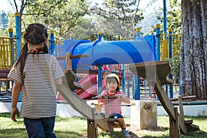 Active little sisters playing on a seesaw in the outdoor playground. Happy child girls smiling and laughing on children playground