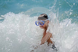 Active little sport boy in diving mask under high sea wave with splash during summer travel holiday recreation vacation