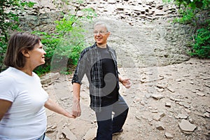 Active loving senior couple walking in beautiful summer forest - active retirement concept.