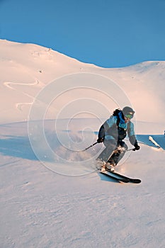Active male freerider speedly ride down snow-covered slopes on fresh powder snow