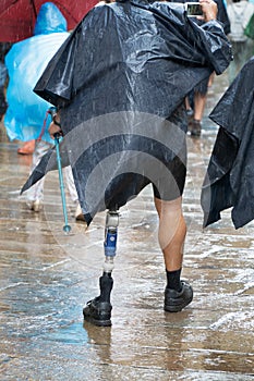 Active male tourist or pilgrim with prosthesis walking on a street of a old town of Santiago de Compostela on a rainy day