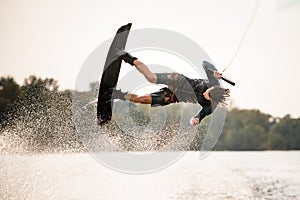 active male wakeboarder doing somersault in the air above water
