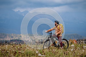 Aktívny muž na bicykli uprostred jesennej prírody, obdivovať hory. Koncept zdravého životného štýlu.