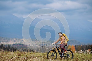 Aktívny muž na bicykli uprostred jesennej prírody, obdivovať hory. Koncept zdravého životného štýlu.