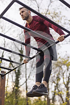 Active man doing pullups while exercising outdoors