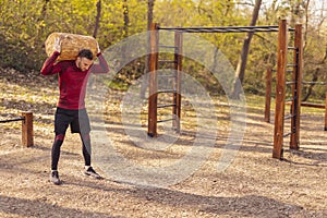 Active man doing squats with weights outdoors