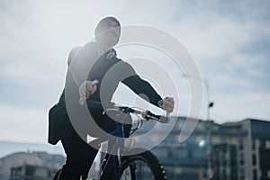 Active man enjoying a bike ride in the city with headphones on a sunny day