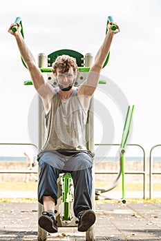 Active man exercising on chest press outdoor.