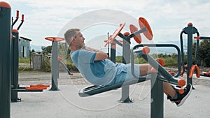 Active man exercising at outdoor gym. Young male doing abdominal muscle exercises on street playground. Fitness, sport