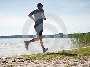 Active man exercising and stretching on the lake beac