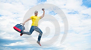 Active man jumping with travel bag midair sky background, copy space
