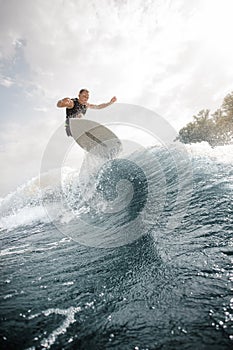 Active man jumping on the white wakeboard on the wave