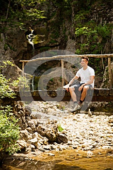 Active man resting on a bridge over mountain creek