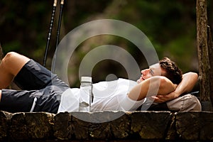 Active man resting on a bridge over mountain creek