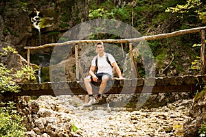 Active man resting on a bridge over mountain creek