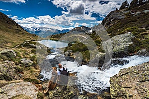 Active man sit on rock with dog while trekking