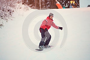 Active man snowboarder in red jacket riding on slope, snowboarding