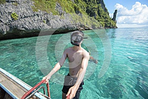 Active man on thai traditional longtail Boat is ready to snorkel and dive, Phi phi Islands, Thailand